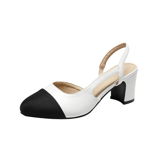 A pair of beige patchwork leather slingback sandals with black accents, displayed on a person's feet with jeans and a flat heel.